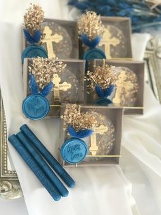 four blue candles are sitting in small boxes on a white tablecloth with gold and blue decorations