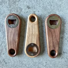 three wooden bottle openers sitting next to each other on a cement surface with one open and the other closed