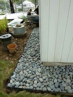 some rocks are laying on the ground next to a white door and potted plants