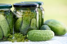 cucumbers and herbs in jars sitting on a table