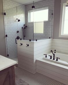 a large bathroom with white tile and black fixtures