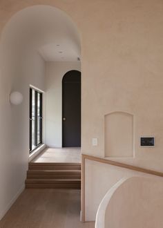 an empty hallway with stairs leading up to the door and windows on either side of the room