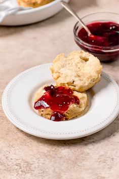 two scones with jam on them sitting on a plate