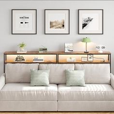 a living room with white couches and three framed pictures on the wall above them