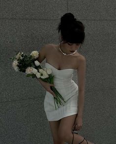 a woman in a short white dress holding flowers