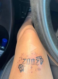 a person with a tattoo on their leg sitting in a car next to a steering wheel