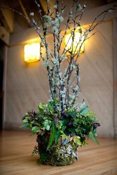 a vase filled with flowers and greenery on top of a hard wood flooring