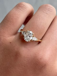 a woman's hand with a diamond ring on top of her finger, showing the side stones