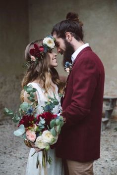 a man and woman standing next to each other in front of a building with flowers on their heads