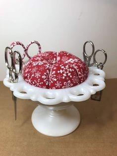 a red and white cake sitting on top of a plate with scissors in the middle