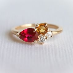 an orange and white diamond ring with two pear shaped diamonds on it's sides