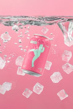 a can of soda floating in the water with ice cubes around it on a pink background