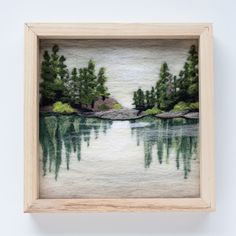 a painting is hanging on the wall next to a frame with water and trees in it