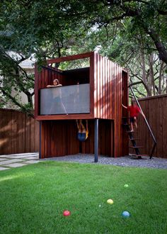 a small wooden structure in the middle of a yard with people climbing on it and ladders going up