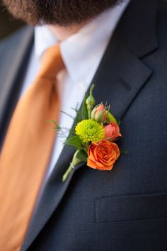 a man in a suit and tie with flowers on his boutonniere,