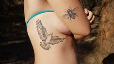 a woman with a tattoo on her side and a bee on her back, standing next to a tree