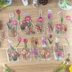 several bottles with flowers in them sitting on a table next to other vases and flowers