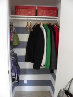 an organized closet with clothes hanging on hooks and storage bins next to the door