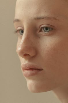 a woman with freckled hair and blue eyes looks off to the side while wearing earrings