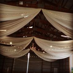 the ceiling is decorated with white drapes and string lights