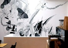 the wall is decorated with black and white flowers, butterflies and plants in an artistic manner