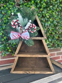 a wooden christmas tree with candy canes on it and greenery in the background