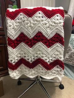 a red and white crocheted blanket sitting on top of a chair