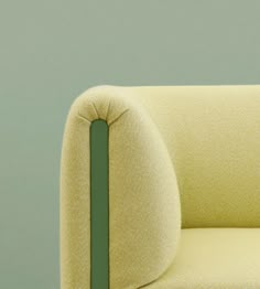 a yellow chair with a green stripe on the armrests and back rest, in front of a blue wall