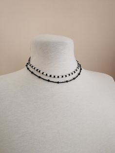 a white mannequin wearing a black and white beaded choker on it's neck