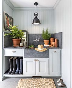 a kitchen with white cabinets and gray counter tops, potted plants on the wall