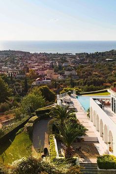 an aerial view of a house with a swimming pool in the foreground and ocean in the background