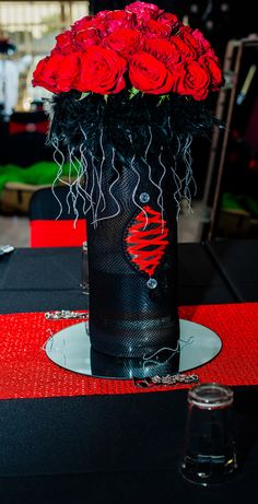 a black vase filled with red roses on top of a table