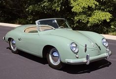 an old green sports car parked in a parking lot