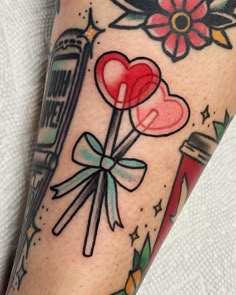 a tattoo on the leg of a person with a flower and heart shaped lollipops