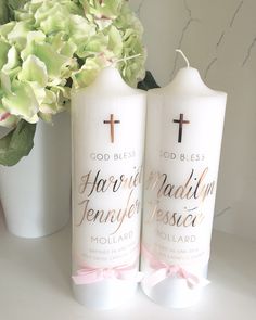 two white candles with pink bows and cross on them