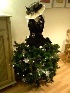 a dress and hat sitting on top of a christmas tree in a room with wooden floors