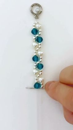 a person is holding onto a blue and white beaded key chain with pearls on it