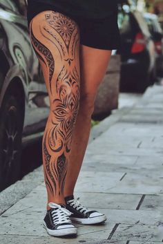 a person with tattoos on their legs standing next to a car