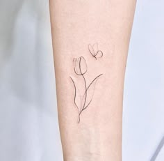 a small flower tattoo on the left inner forearm and wristband is shown in black ink