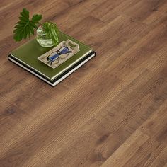 a book with glasses on top of it sitting on a table next to a plant