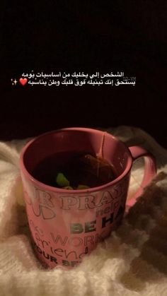 a pink cup filled with liquid sitting on top of a blanket