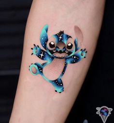 a small tattoo on the arm of a person with a blue and black frog design