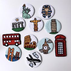 six embroidered badges depicting different sights around the world on a white surface, including a red bus, a statue of liberty, a blue bus and a green fire hydrant