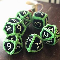 four green and black dices sitting on top of a table next to a cup