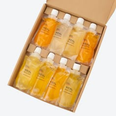 six bottles of orange and yellow liquid in a cardboard box