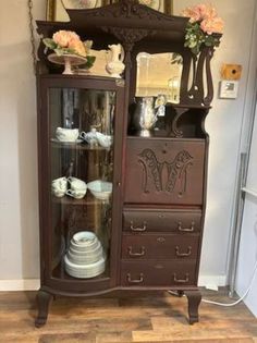 an antique china cabinet with glass doors and drawers