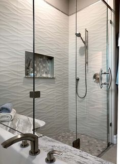 a bathroom with a walk in shower next to a white sink and glass doored shower