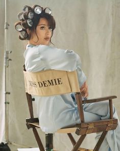 a woman sitting on top of a wooden chair with hair dryers in her hair