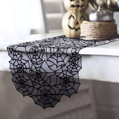 a black lace table runner sitting on top of a white table next to vases