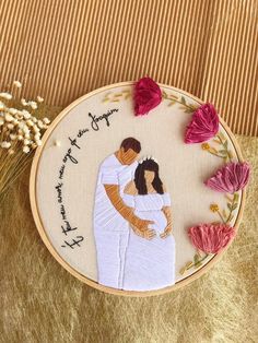 a couple is hugging each other in front of some flowers on a gold cloth background